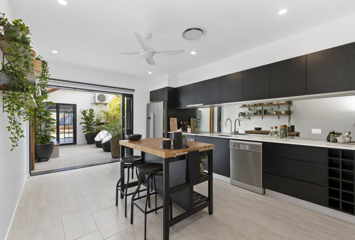 Kitchen area with central isnland bench and greenery dark cabinets and white ceiling