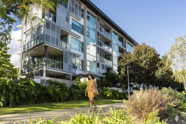 Woman walking along path infront of 5 storey apartment complex