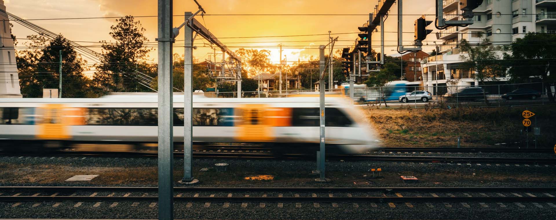 Looking over trainlines at a sunset with a train blurred out as it passes through
