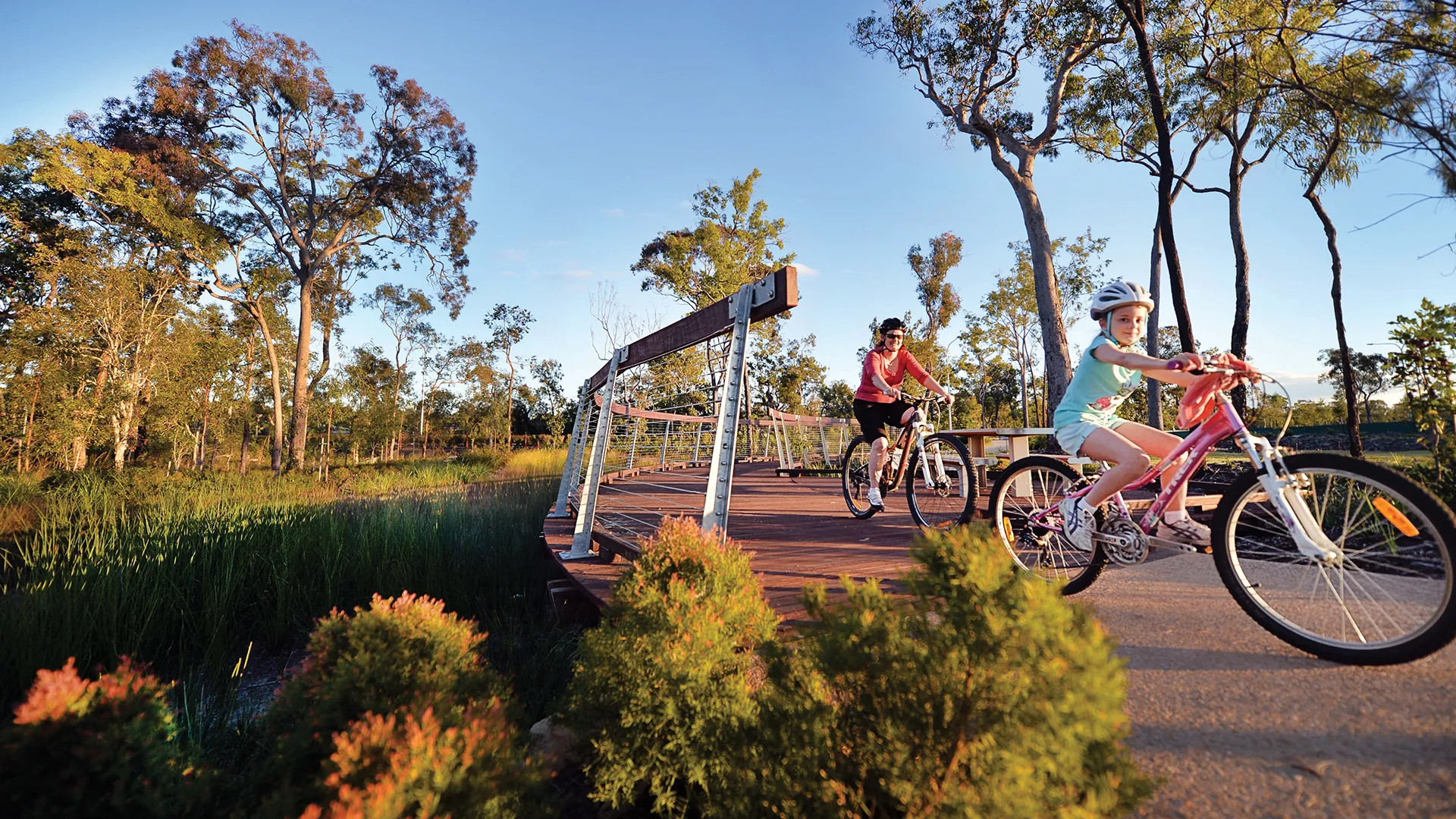 Two people riding bicycles on a path surrounded by trees
