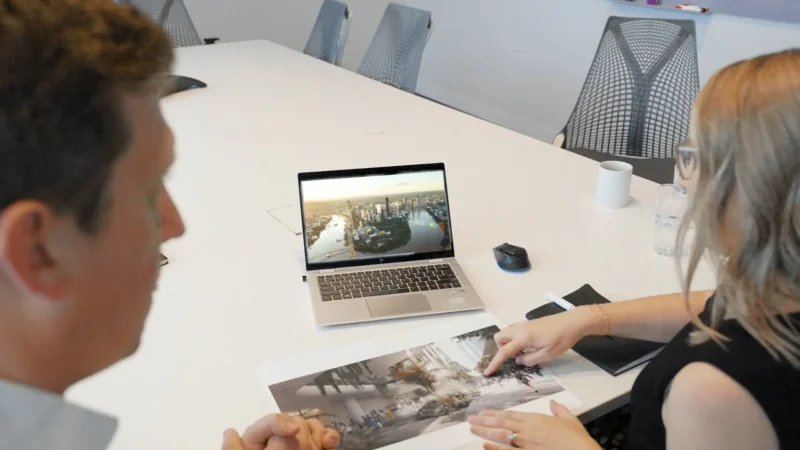 People interacting with laptop and documents in a meeting