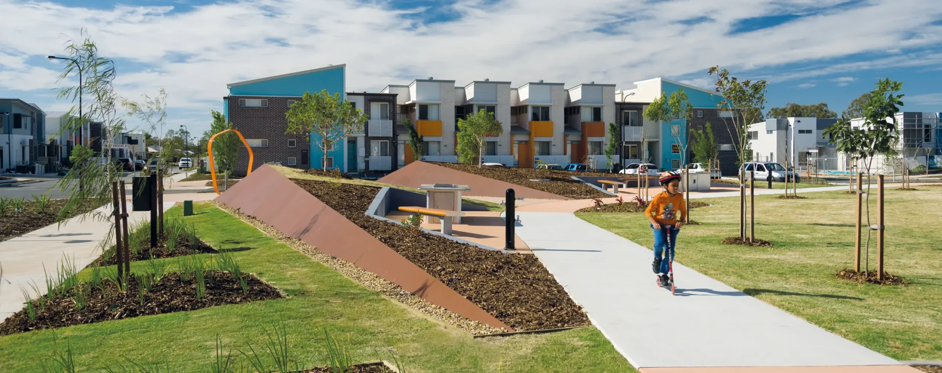 Individual riding a scooter on a path through a neighbourhood park