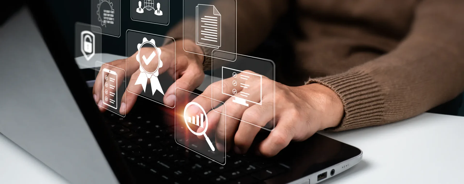 Hands interacting with a laptop showing digital icons of tools and files