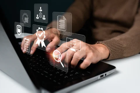 Hands interacting with a laptop showing digital icons of tools and files