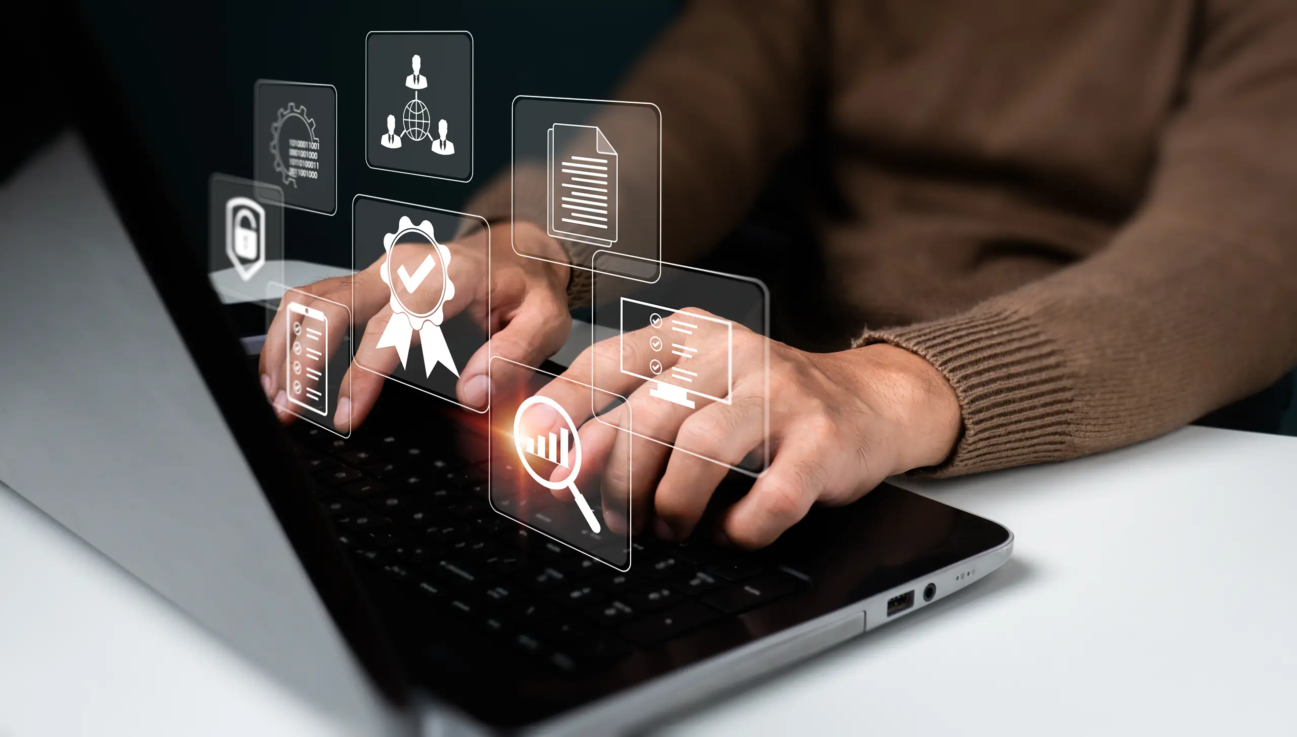 Hands interacting with a laptop showing digital icons of tools and files