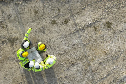 A group of people in hi-vis jackets looking at a plan on site