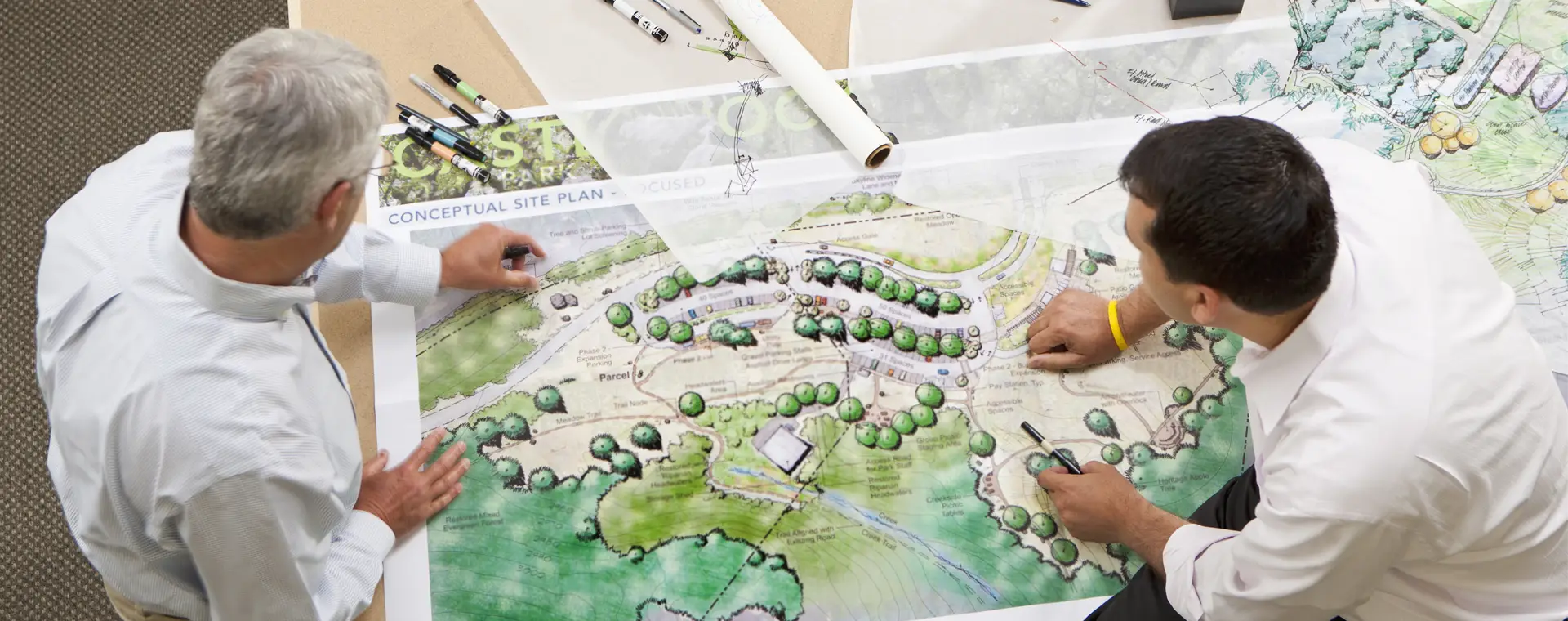 People looking at plans spread out over a table