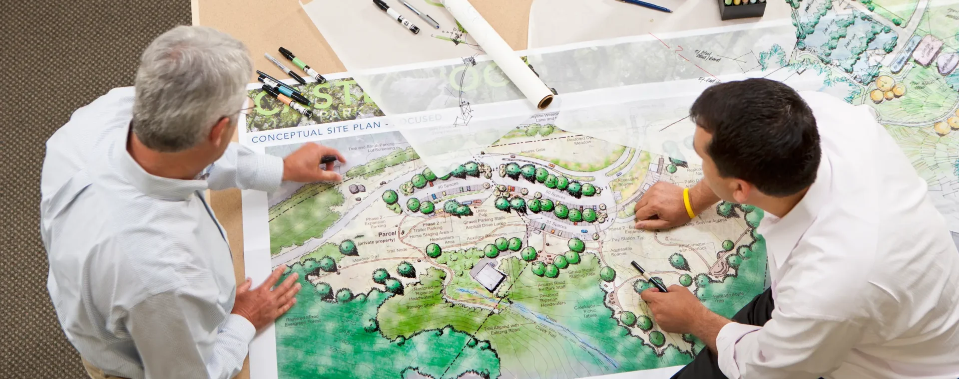 People looking at plans spread out over a table