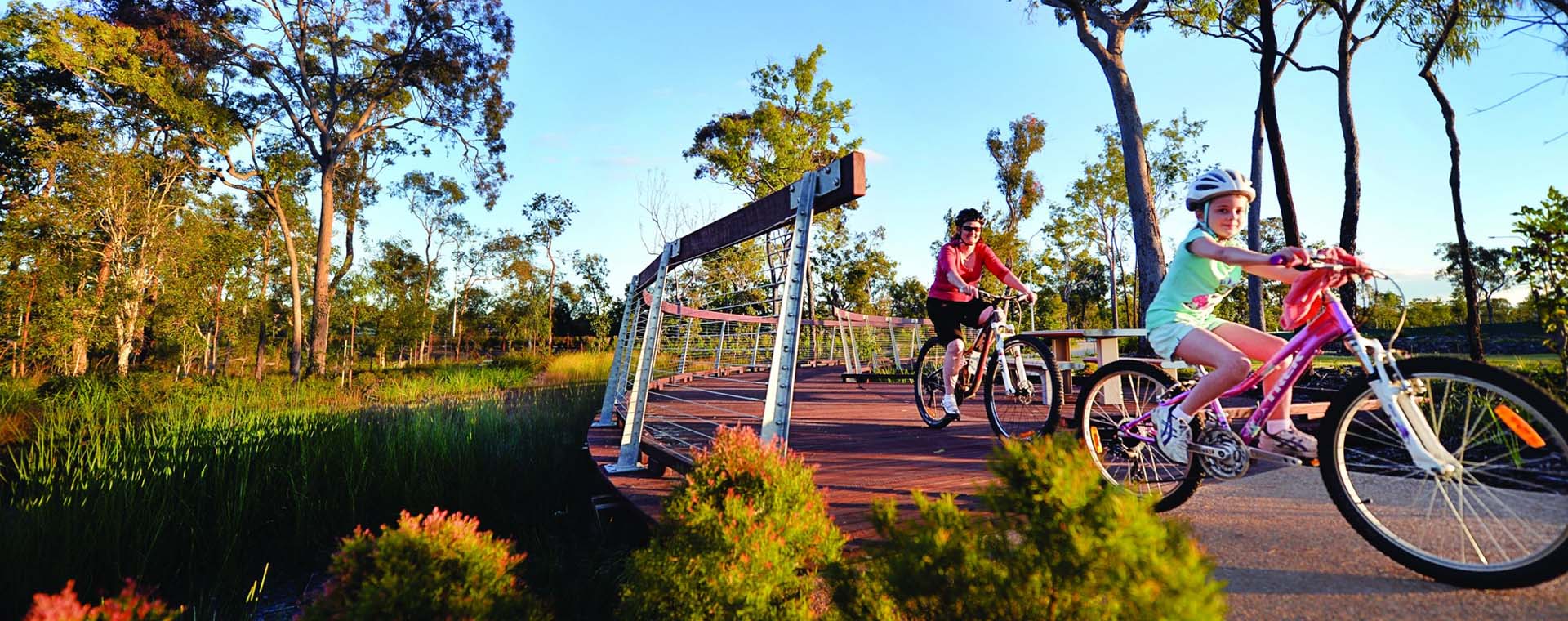 Two people riding bicycles on a path surrounded by trees
